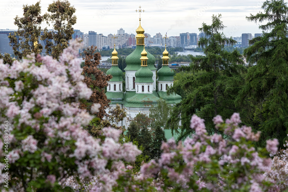 Green domed Orthodox church framed by spring lilac blossom