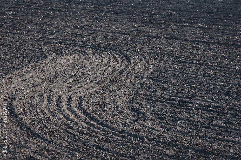 Naklejka premium Patterns of freshly plowed earth create a tapestry of textures in an agricultural field under the midday sun in early spring