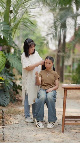 Asian mother braids her daughter's hair