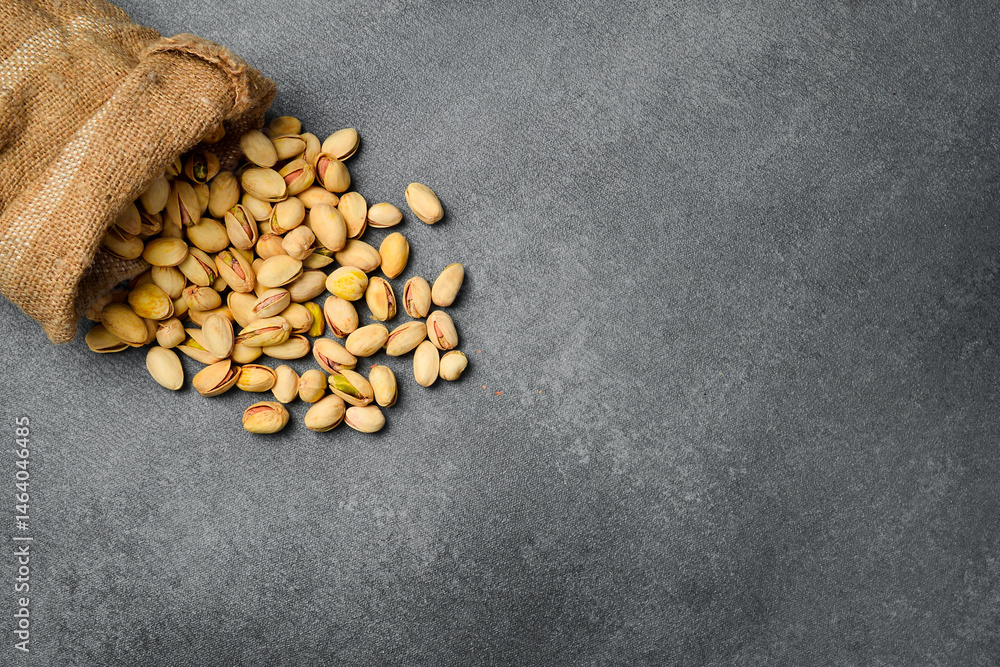 Linen bag with pistachios. Salted nuts. On a gray concrete background. Top view, free space for text. Linen bag with pistachios. Salted nuts. On a gray concrete background. Top view, free space for text.