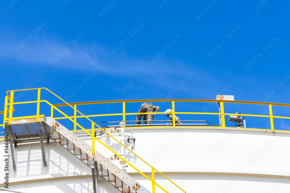 Industrial engineer work on top of crude oil storage tank, Two male worker inspection on the top of oil storage tank inspection visual check oil storage tank, Industrial worker on oil storage tank.
