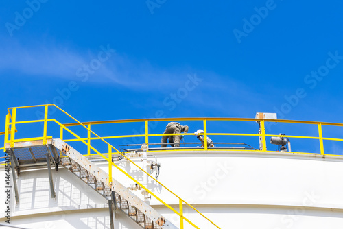 Obraz na płótnie Industrial engineer work on top of crude oil storage tank, Two male worker inspection on the top of oil storage tank inspection visual check oil storage tank, Industrial worker on oil storage tank. w salonie