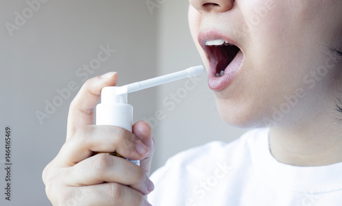 Woman is using mouth spray oral hygiene. Sore throat treatment