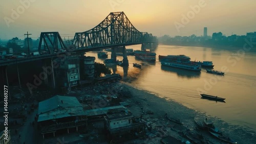 Wide angle drone shot, crowded traffic passing over Calcutta's iconic 'Howrah Bridge' and the Hooghly River flowing underneath. 