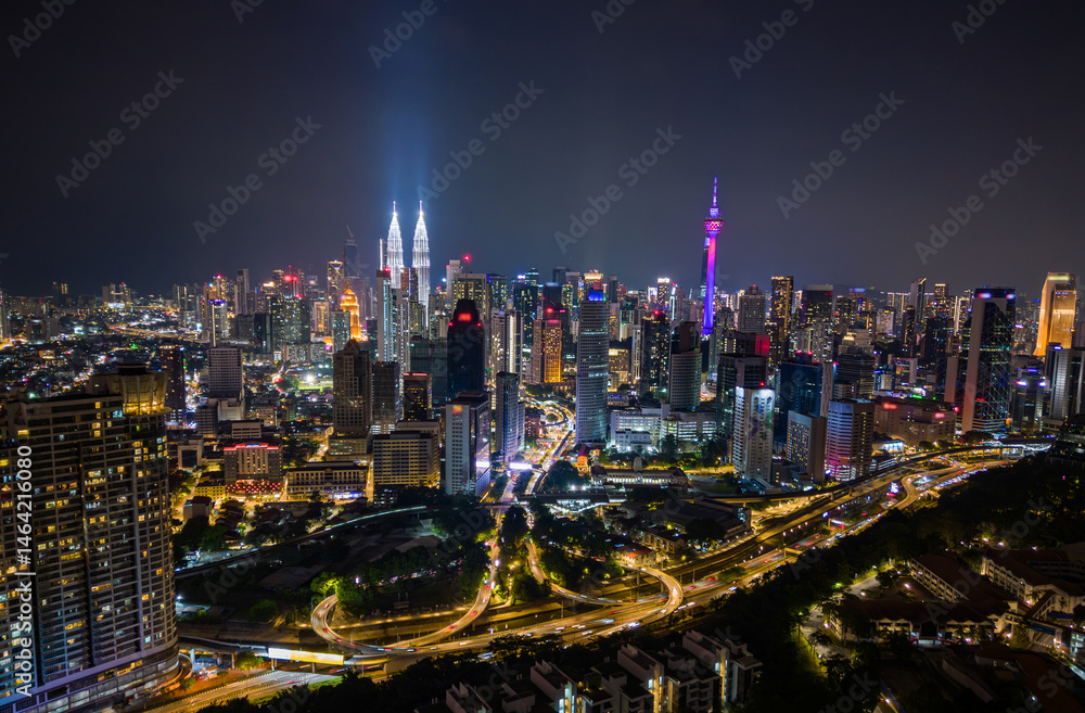 Fototapeta premium Aerial view of Kuala Lumpur city skyline at night with glowing skyscrapers and illuminated roads