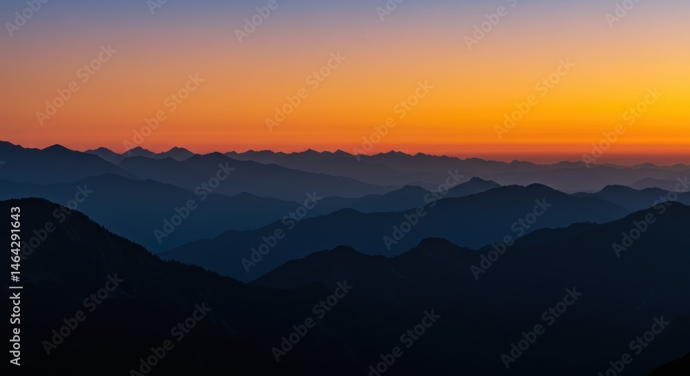 Obraz premium The sunrise over the mountains glows orange, casting warm light across the peaks and creating a breathtaking morning landscape.