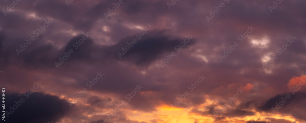 Stunning dramatic sunset background with lilac purple clouds and orange sky firmament texture Stunning dramatic sunset background with lilac purple clouds and orange sky firmament texture