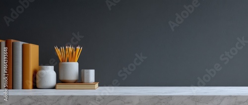 Obraz na płótnie A minimalist desk with books, jars of pencils, and a marble surface against a dark wall. w salonie