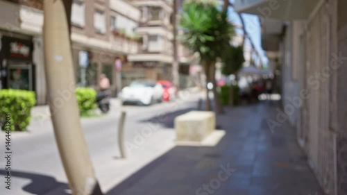 Wallpaper Mural Defocused street scene with blurred buildings, cars, palm tree, and pedestrians in a sunny urban area Torontodigital.ca