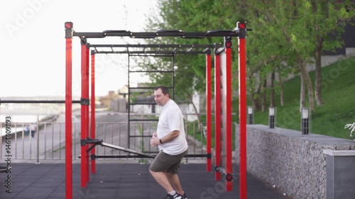 Fat man doing gymnastics to lose weight on the sports ground