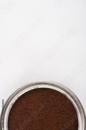 Obraz na płótnie A close-up shot shows a silver rimmed container filled with dark brown instant coffee granules against a bright white background w salonie