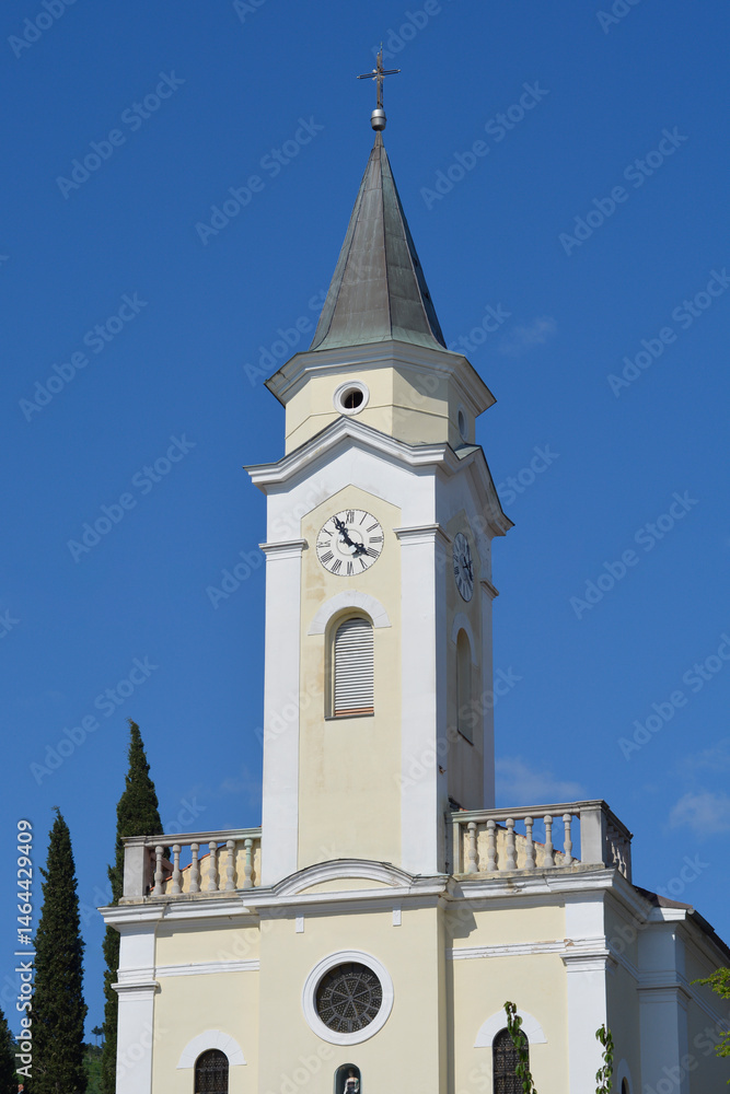 A detailed view captures the clock tower and upper facade of the Church of Saint Catherine in Selce against a clear blue sky