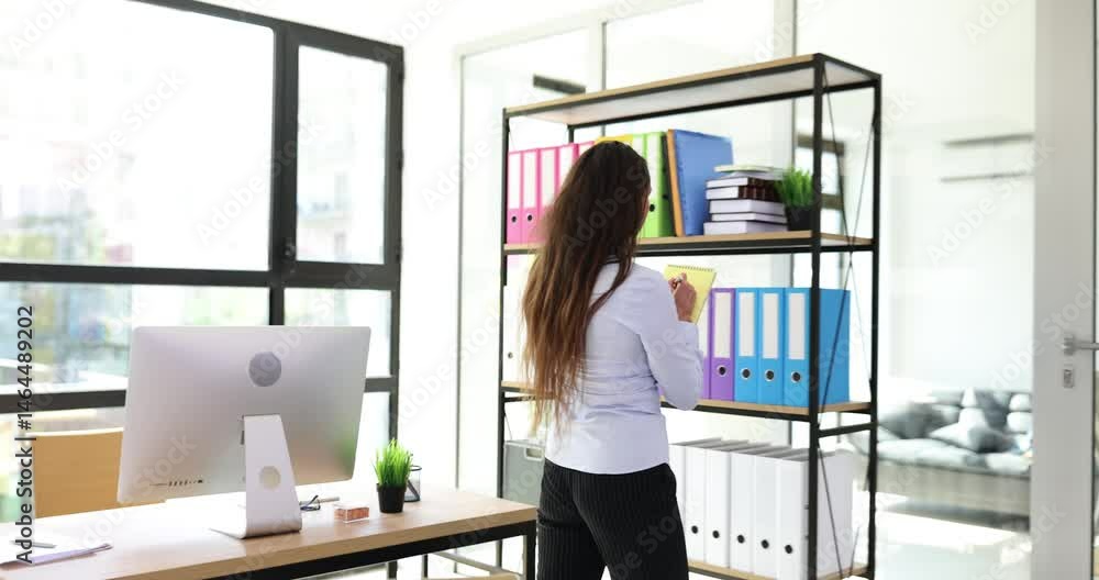 Businesswoman writes notes on notepad walking around modern office. Confident woman entrepreneur prepares presentation for board meeting at workplace Businesswoman writes notes on notepad walking around modern office. Confident woman entrepreneur prepares presentation for board meeting at workplace