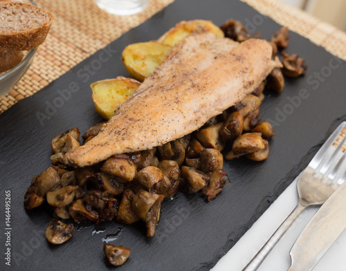 Obraz na płótnie Fried trout fillet on pillow of fried champignon mushrooms on dark warm stone plate w salonie