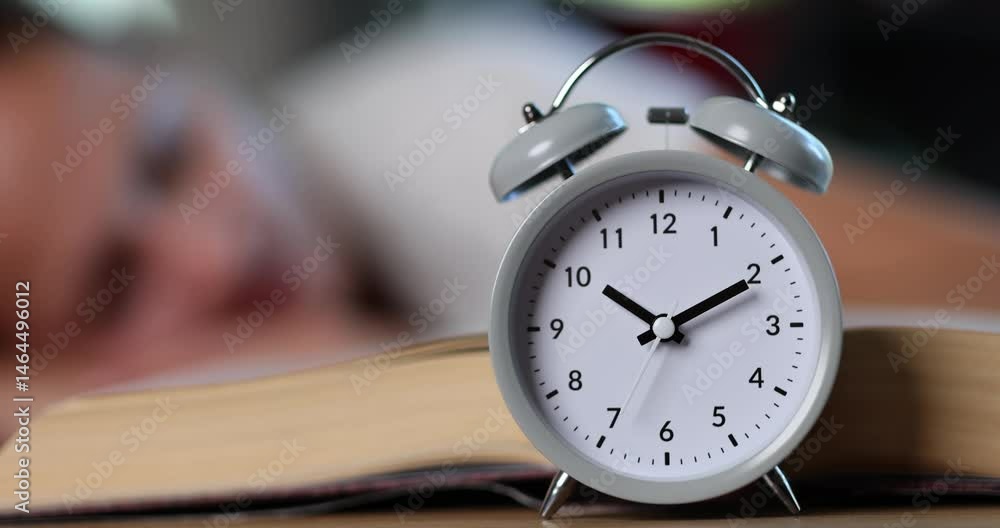 Alarm clock near open book and tired woman student head put on desk ...