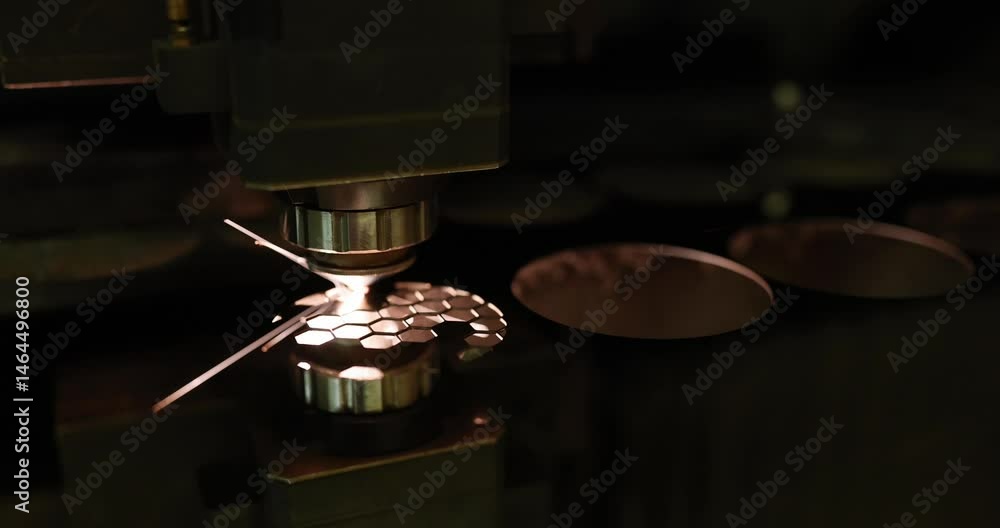 Industrial laser cutting machine processes metal part in workshop at darkness. Machine generates sparks demonstrating precision in modern factory