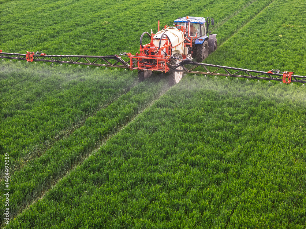 Fototapeta premium Close-up of a farmer spraying crop field with red machinery sprayer. Aerial spraying crops