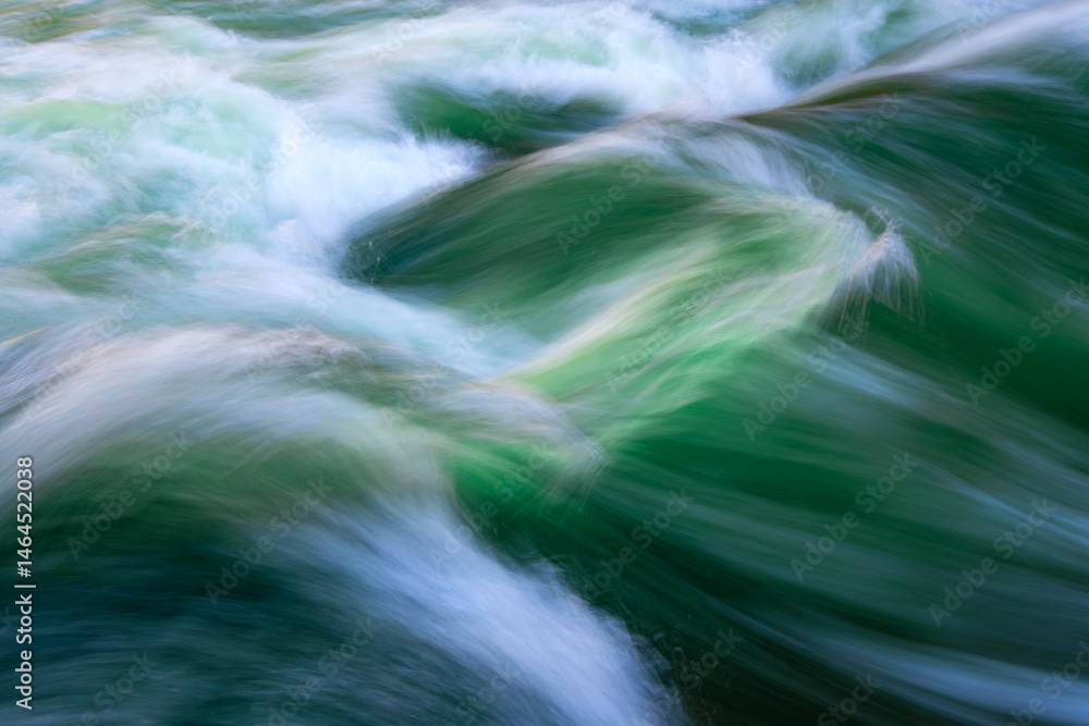 Fototapeta premium Colorful standing wave of the “Eisbach” creek in Munich (Germany). Popular attraction in the English Garden of the Bavarian capital. Motion blur due to long time exposure of powerful river current.