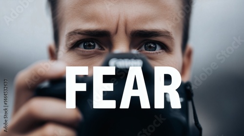Obraz na płótnie Fearful eyes behind camera lens, Close-up of person holding camera with FEAR text, Perfect for fear and media symbolism concepts w salonie