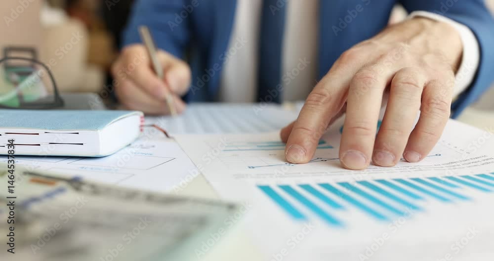 Businessman analyzes financial charts making investment decisions in office. Specialist compares various factors and important data at workplace