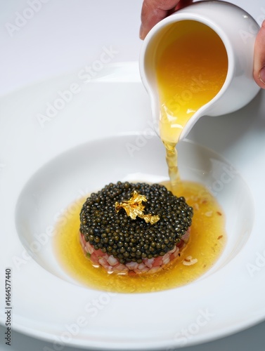 Obraz na płótnie A skilled chef pours a luxurious sauce over a beautifully plated gourmet dish featuring caviar and finely chopped ingredients. The elegant presentation highlights the culinary artistry w salonie