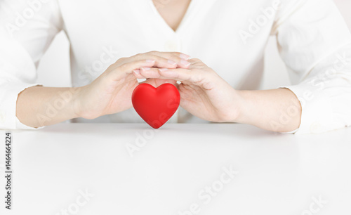 Red Heart Being Protected by Two Gentle Hands on White Background