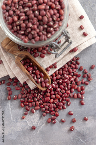 Obraz na płótnie Glass jar full of dried azuki beans with a wooden scoop top view. Vegetarian protein source w salonie