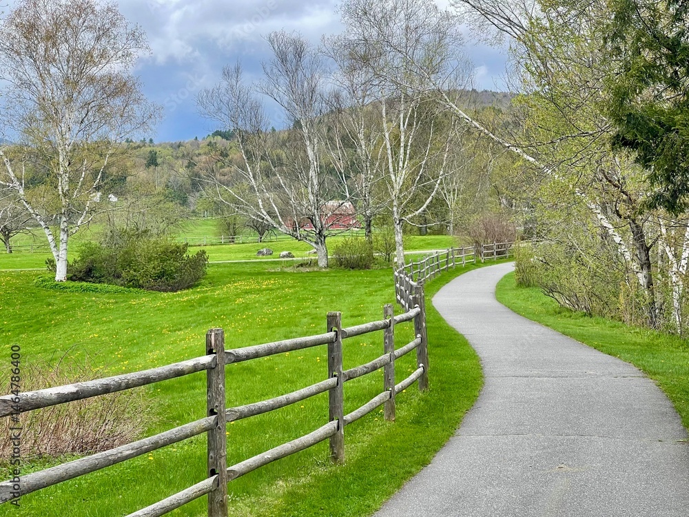 Fototapeta premium Walking bike path winds through the green countryside, farms, and mountains of Vermont in this picturesque scene