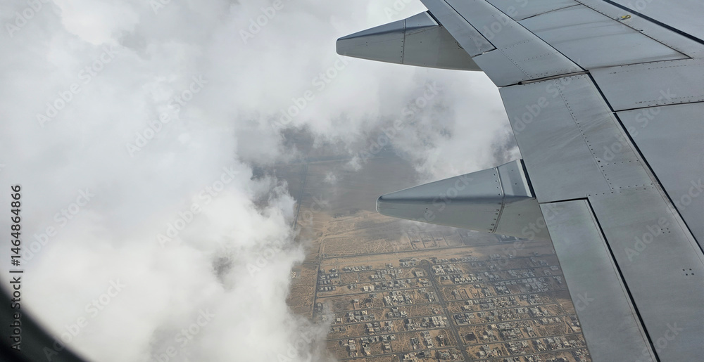 Fototapeta premium Aerial view from high altitude of distant city covered with puffy cumulus clouds forming before rainstorm