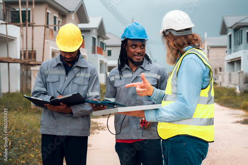 Construction engineers and their team are discussing the site preparation plan for installing solar panels, setting up the working system for an energy-saving housing project and exterior overview.
