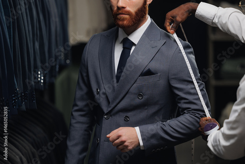 Принти на полотні Professional tailor measuring customer for bespoke suit in menswear store