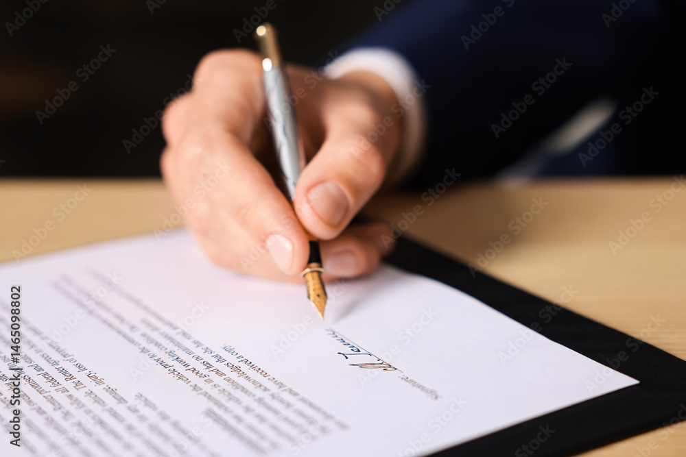 Man putting signature on document at table, closeup Man putting signature on document at table, closeup