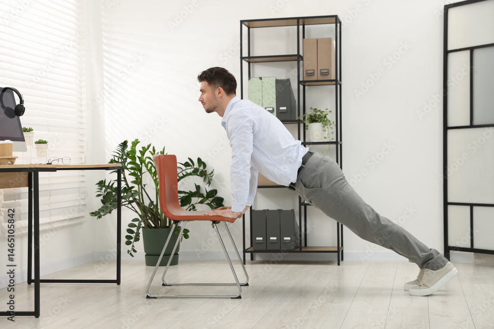 Handsome man exercising with chair in office Handsome man exercising with chair in office