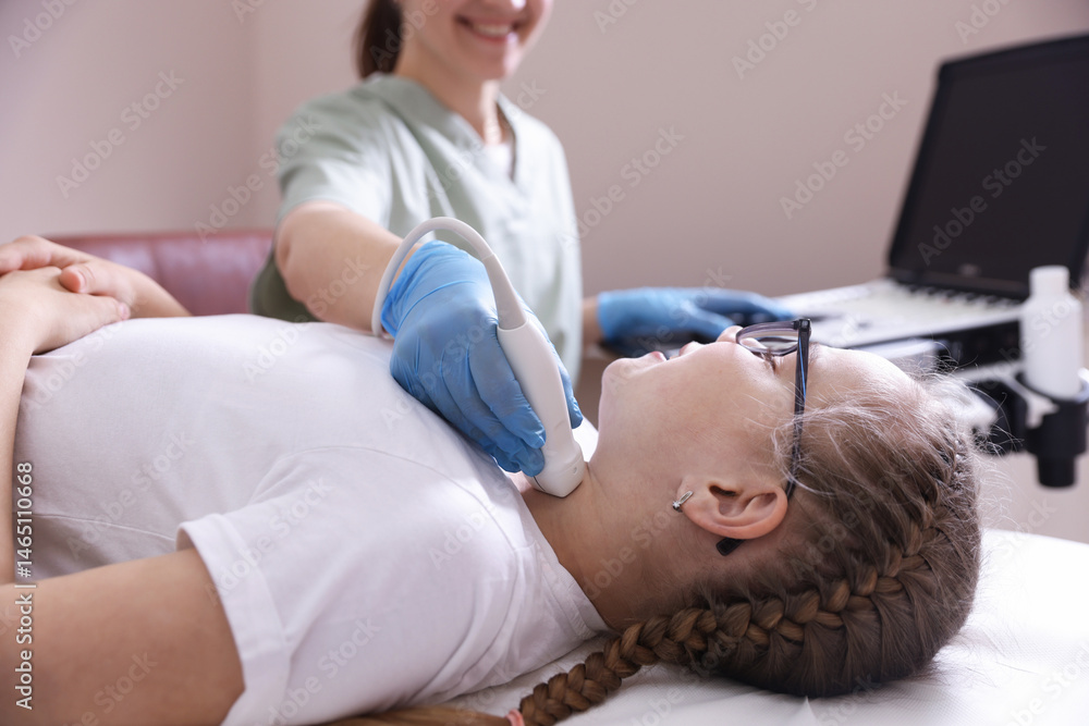 Fototapeta premium Sonographer conducting girl's thyroid gland ultrasound examination in clinic, closeup