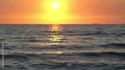 Amazing sunset panorama over tropical calm sea with golden reflections on the water and distant boat under setting sun