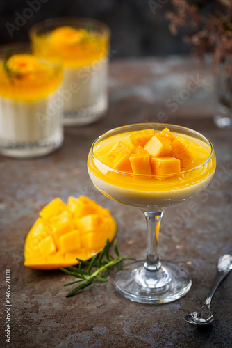 Italian dessert panna cotta with mango in glass on gray background