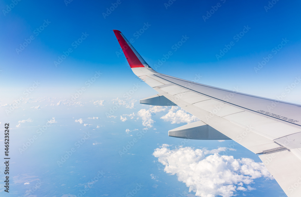 Fototapeta premium View from the airplane window at a beautiful cloudy sky and the airplane wing