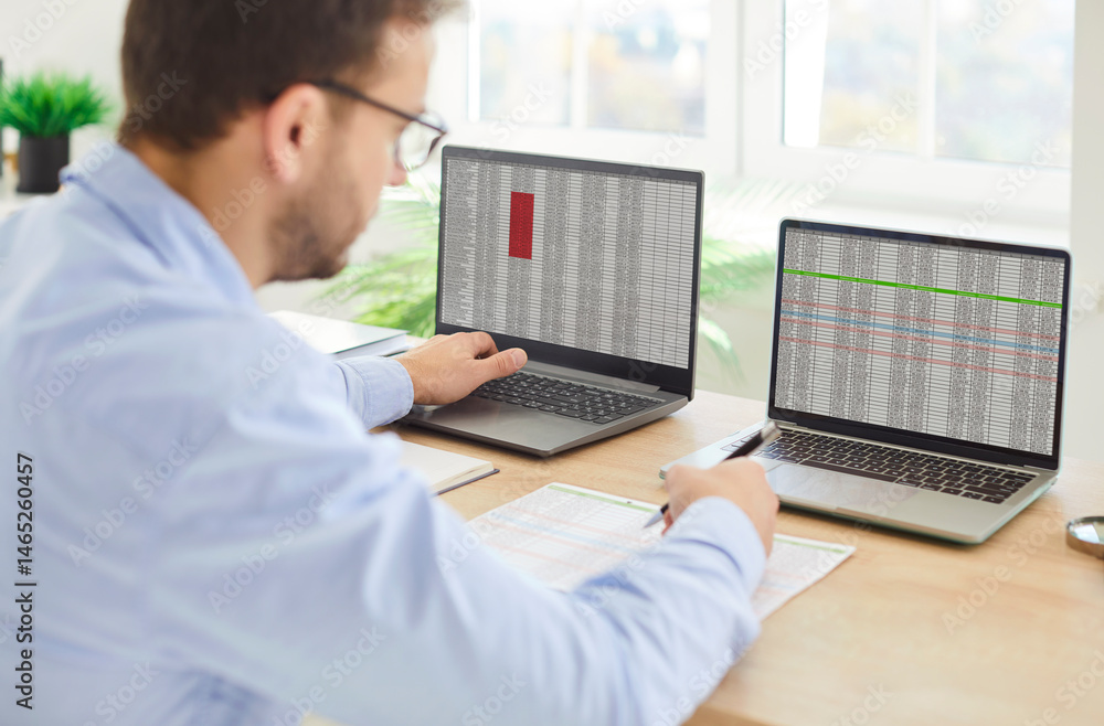 Young confident business man accountant working at the desk on workplace on a laptop with tables and charts in office analyzing company finances. Accounting and data analysis concept. Young confident business man accountant working at the desk on workplace on a laptop with tables and charts in office analyzing company finances. Accounting and data analysis concept.
