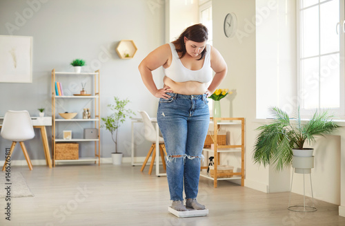 Fotografía Young fat overweight woman in casual clothes looking on the scales at home