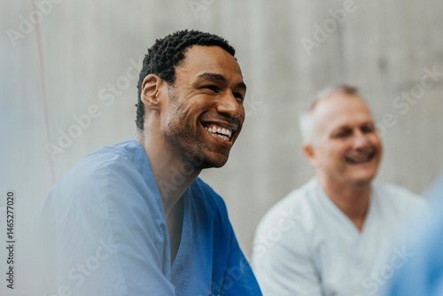 Happy male healthcare worker enjoying with medical team in hospital