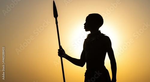 Fototapeta Naklejka Na Ścianę i Meble -  Silhouette of an african warrior with spear against a golden sunset backdrop