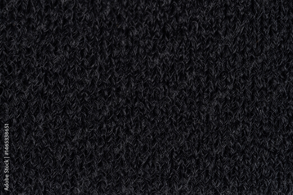 Dark textured knit fabric showcasing close-up of intricate knitting patterns
