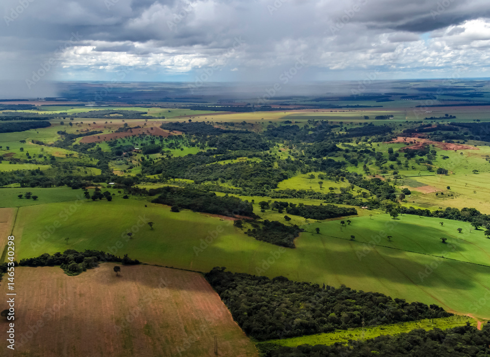 Aerial view of Brazilian farmland under a stormy sky, showcasing agriculture and climate impact