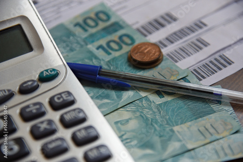 Real - Brazilian currency. Real notes on a wooden table with a calculator and pen in the composition. Concept of economy, finance, Selic rate, taxes and financial planning