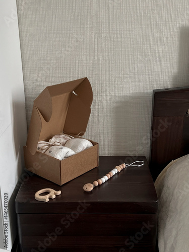 Obraz na płótnie A box of muslin diapers, beads, and a wooden elephant teether are on the bedside table. Fashionable Scandinavian accessories for newborns on the bedside table w salonie