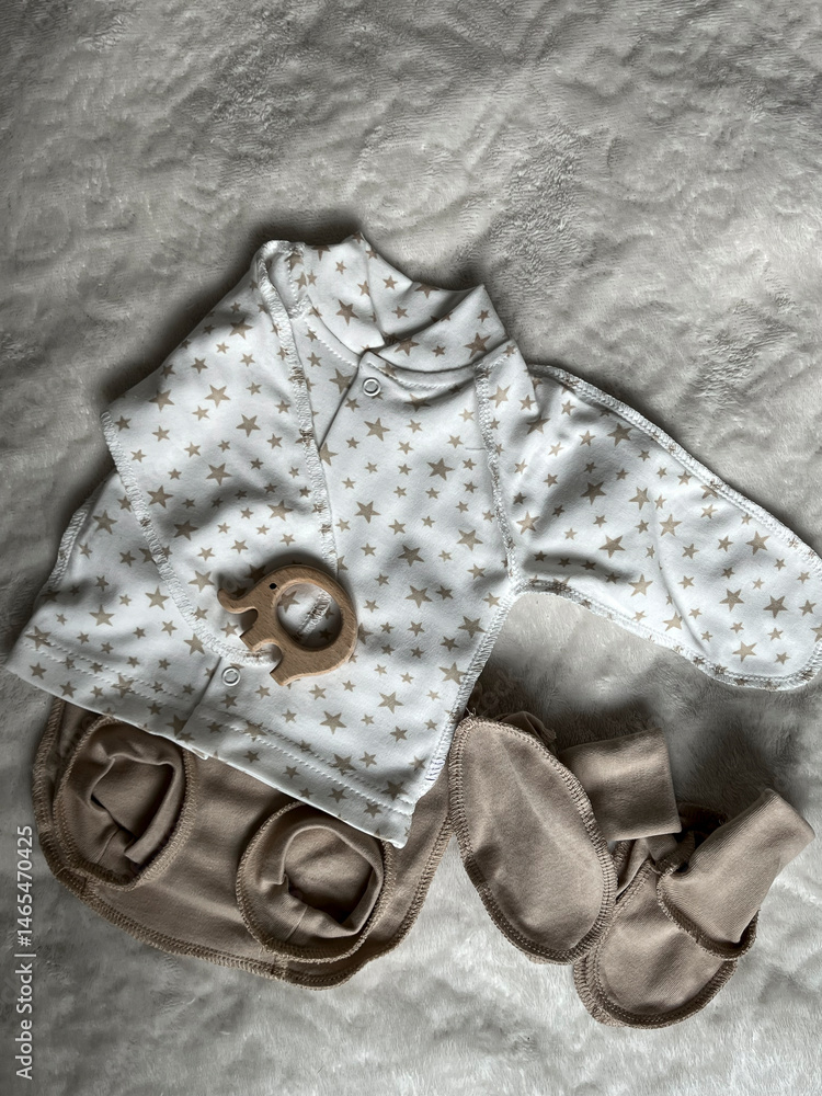 A turtleneck, diaper panties, socks, a wooden elephant teether. Cute pastel-colored clothes, accessories for newborns. Flatley, top view