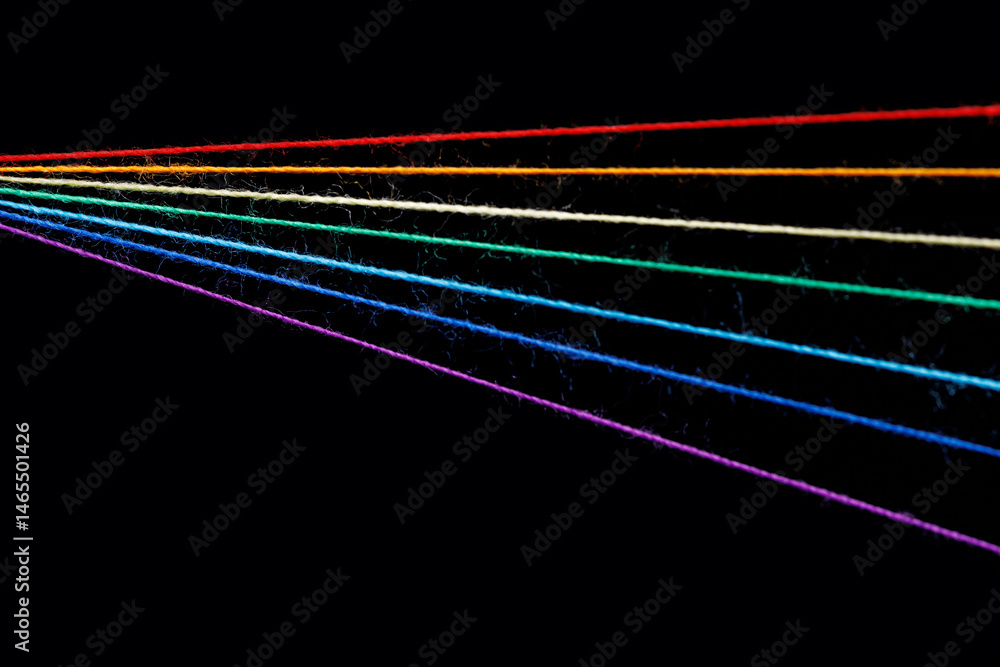 multicolored sewing threads in the form of a rainbow on a black background