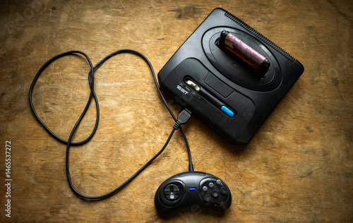 A game console with a connected cable and controller.A 16-bit game console.