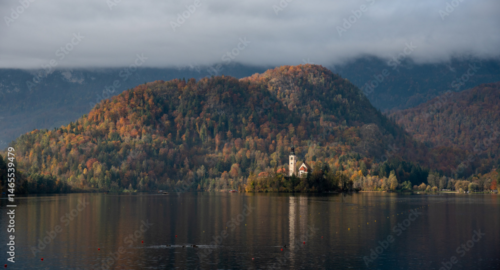 Assumption of mary pilgrimage church on lake bled, surrounded by mountains and colorful autumn foliage, in slovenia