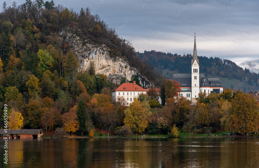 St. Martin's parish church reflecting on lake bled during a cloudy autumn day